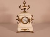 a small white clock with a gold decoration on it