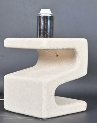a white concrete table with a lamp on top of it