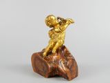 figurine en or représentant un garçon jouant de la flûte sur un rocher