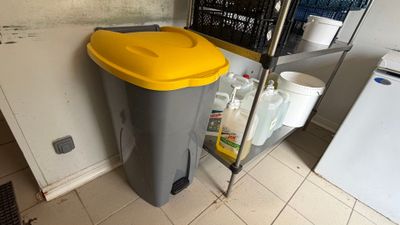 a trash can sitting next to a refrigerator in a kitchen