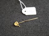 un gros plan d'une broche en or à laquelle est accrochée une étiquette