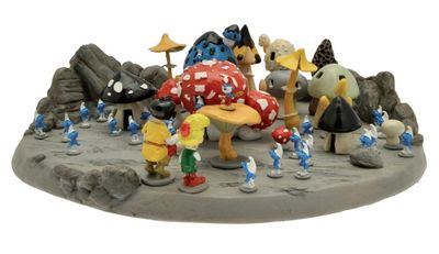 figurines représentant un groupe de Schtroumpfs rassemblés autour d'un champignon posé sur un rocher