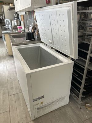 un réfrigérateur qui se trouve dans une cuisine, à côté d'une étagère