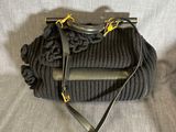 un sac à main en tricot gris auquel est attaché un téléphone portable