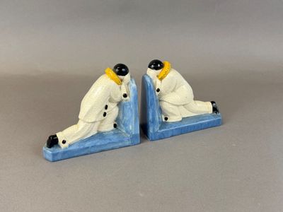 pair of ceramic figurines of a man and a woman sitting on a bookends
