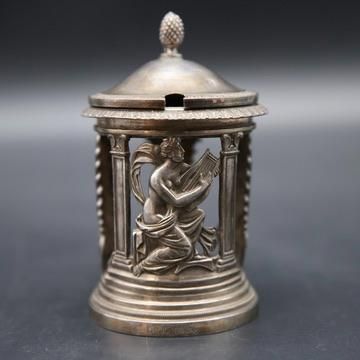 an antique silver figurine of a woman playing the harp