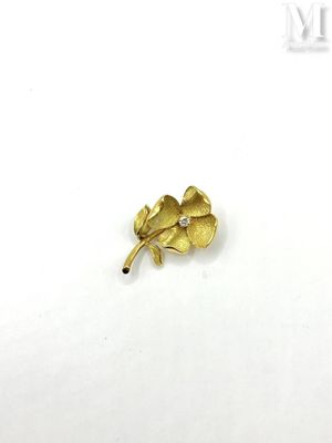 a close up of a gold flower brooch on a white surface