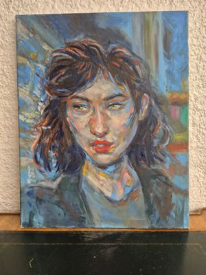 painting of a woman ' s face on a shelf in front of a white wall