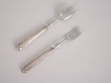 two forks and a spoon on a white table