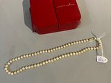 une boîte rouge contenant un collier de perles blanches et une boîte rouge contenant un collier de perles blanches