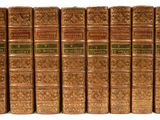 six vieux livres sont alignés sur une surface blanche
