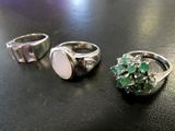 three rings with green and white stones sitting on a table