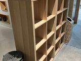 a wooden book shelf with a trash can in the corner