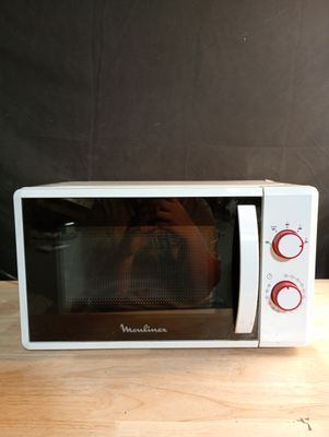 Quelqu'un prend une photo d'un micro-ondes posé sur une table en bois.
