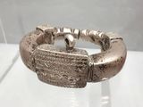 bracelet en argent exposé dans une vitrine, posé sur un fond blanc