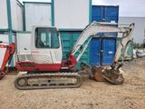 an image of a small excavator parked in front of a building