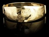 gros plan d'un bracelet en or sur une surface noire