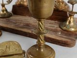 a gold cup on a wooden stand next to other brass objects