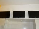 three flat screen tvs mounted on the wall above a sink