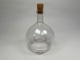 an empty glass bottle with a cork stopper sitting on a table