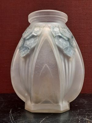 un vase blanc posé sur une table, avec un mur rouge en arrière-plan