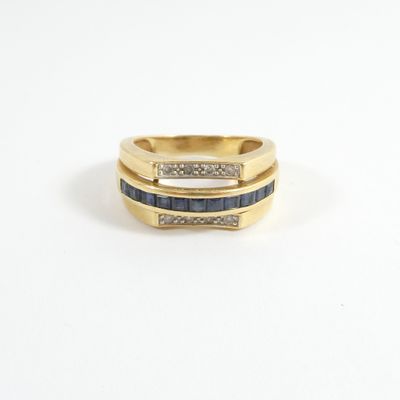 gros plan d'une bague en or avec des pierres bleues et blanches
