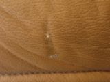 the back of a brown leather chair with holes in it
