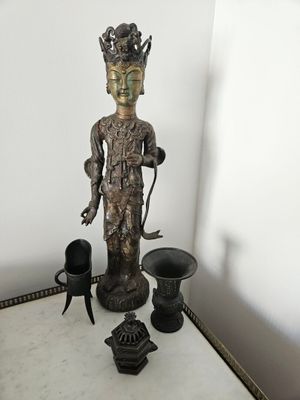 une statue posée sur une table, à côté d'autres objets
