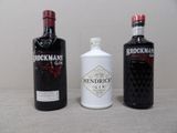 Trois bouteilles de gin sont alignées sur une table