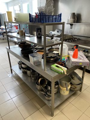 de nombreuses casseroles et poêles posées sur une étagère métallique dans la cuisine