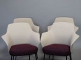 deux chaises blanches aux coussins violets et aux pieds noirs, adossées à un mur gris