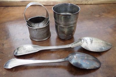 trois cuillères en argent et deux tasses en argent posées sur une table