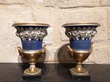 deux vases posés sur une table, avec un mur de pierre en arrière-plan