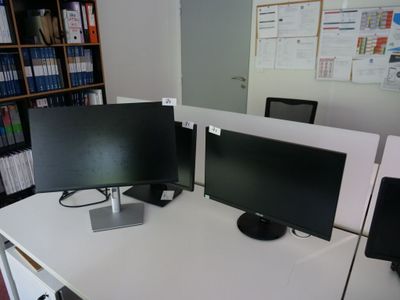 deux écrans d'ordinateur posés sur un bureau dans un bureau