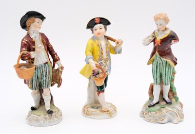 three figurines of a man and a woman holding a basket