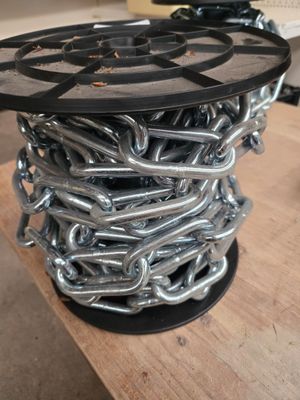 une bobine de chaînes posée sur une table en bois