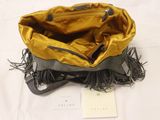 yellow and black handbag with fringes on a white bed