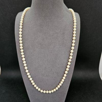 un collier de perles blanches sur un mannequin avec un fermoir en or