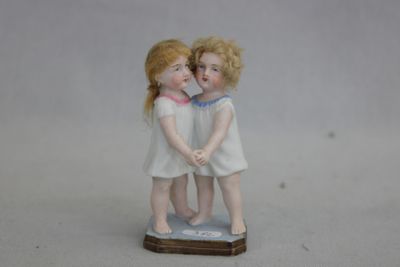 une petite figurine représentant deux enfants debout sur une table
