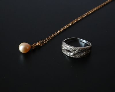 une image représentant une bague et une perle sur un fond noir