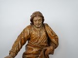 a wooden statue of jesus sitting on a bench