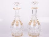 deux bouteilles en verre transparent ornées de motifs dorés