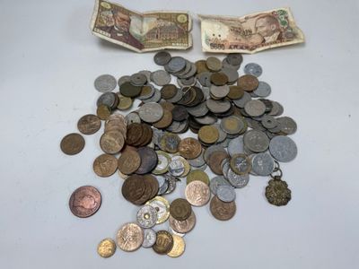 une pile de pièces posée sur une table, à côté d'un portefeuille