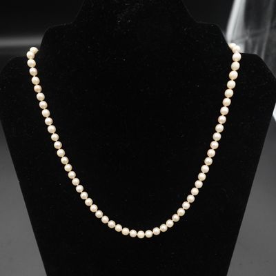 un collier de perles blanches sur un mannequin noir