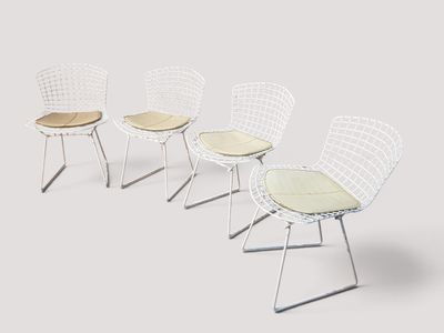 quatre chaises blanches alignées, chacune munie d'un coussin