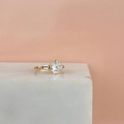 un gros plan d'une bague de fiançailles en diamant posée sur un bloc de marbre