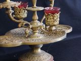 a three - tiered candle holder with red glass cups on it