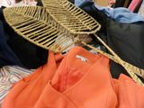 a pile of clothes and a wicker hat on a bed