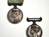 deux médailles d'argent ornées d'un ruban, posées sur un fond blanc