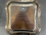 a silver tray with a handle on a stand on a table
